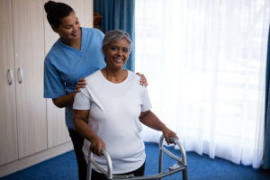 Nurse helping patient with walker in skilled nursing facility